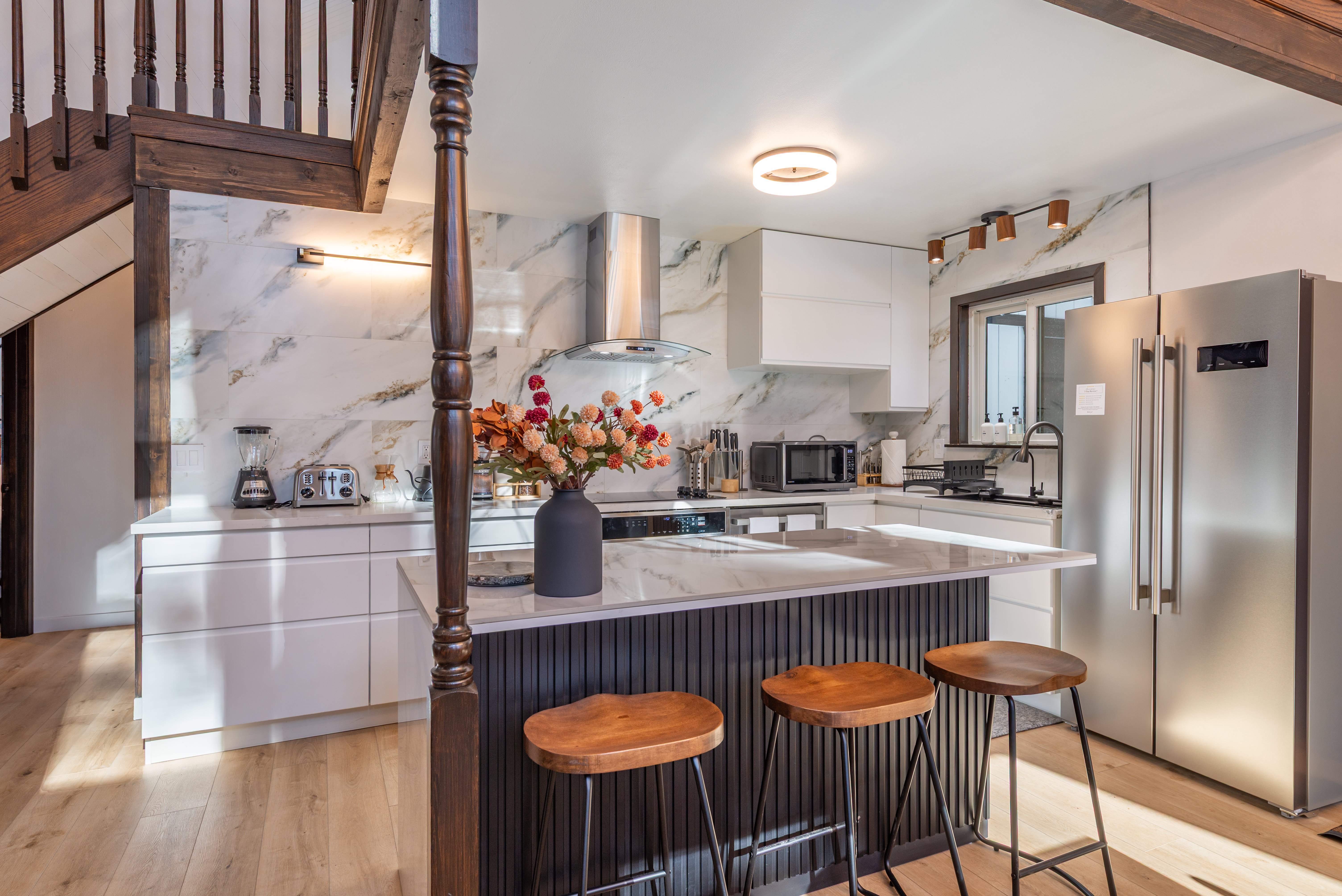 Refreshed kitchen with marble waterfall island and bar seating